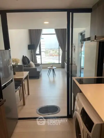 Modern apartment with open kitchen and living room, featuring large windows and stylish decor.
