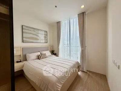 Modern bedroom with large window and stylish decor in a high-rise apartment.