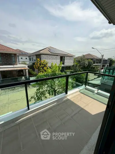 Spacious balcony with glass railing offering a serene neighborhood view
