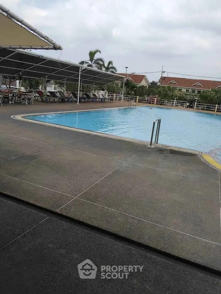 Spacious outdoor pool area with lounge chairs and canopy, perfect for relaxation.