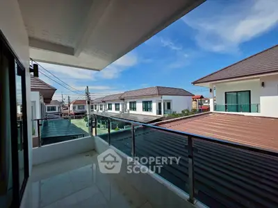 Spacious balcony with modern railing overlooking residential neighborhood under clear blue sky.