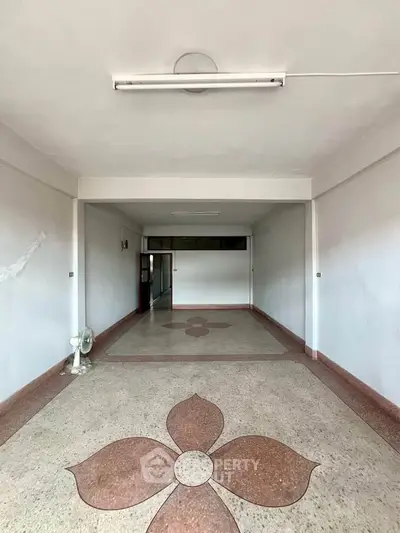 Spacious empty room with unique floral floor design and bright lighting, ideal for customization.