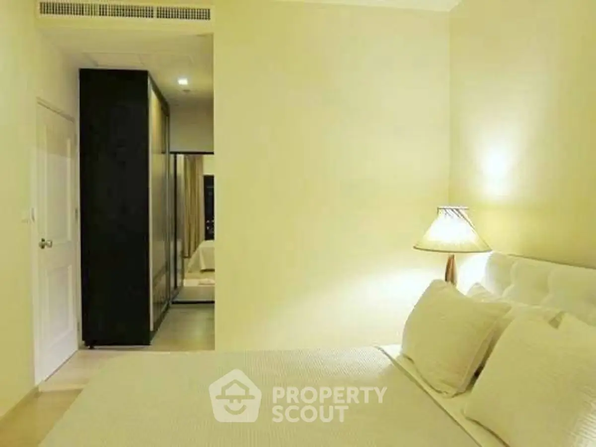 Elegant bedroom with soft lighting and modern decor, featuring a cozy bed and stylish lamp.