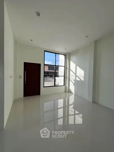 Spacious modern living room with large window and glossy white flooring