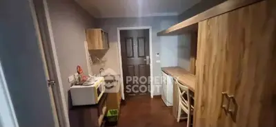 Compact kitchen with modern appliances and wooden cabinetry in cozy apartment.