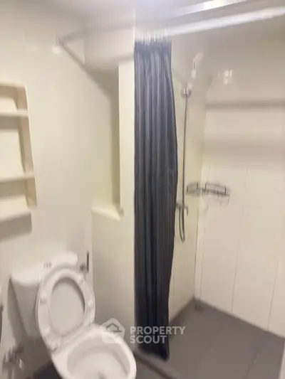 Compact bathroom with shower curtain and toilet in modern apartment.
