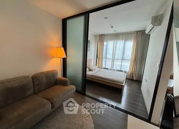 Modern apartment with cozy living room and bedroom separated by sliding glass doors, featuring stylish decor.