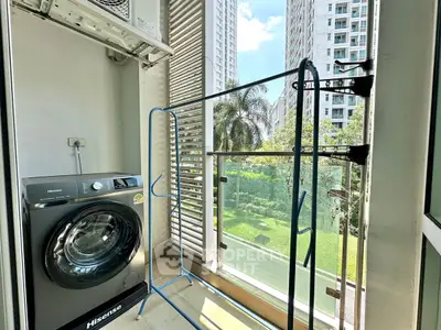 Modern apartment balcony with washing machine and lush garden view