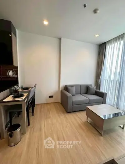 Modern living room with cozy gray sofa and dining area in open layout apartment.