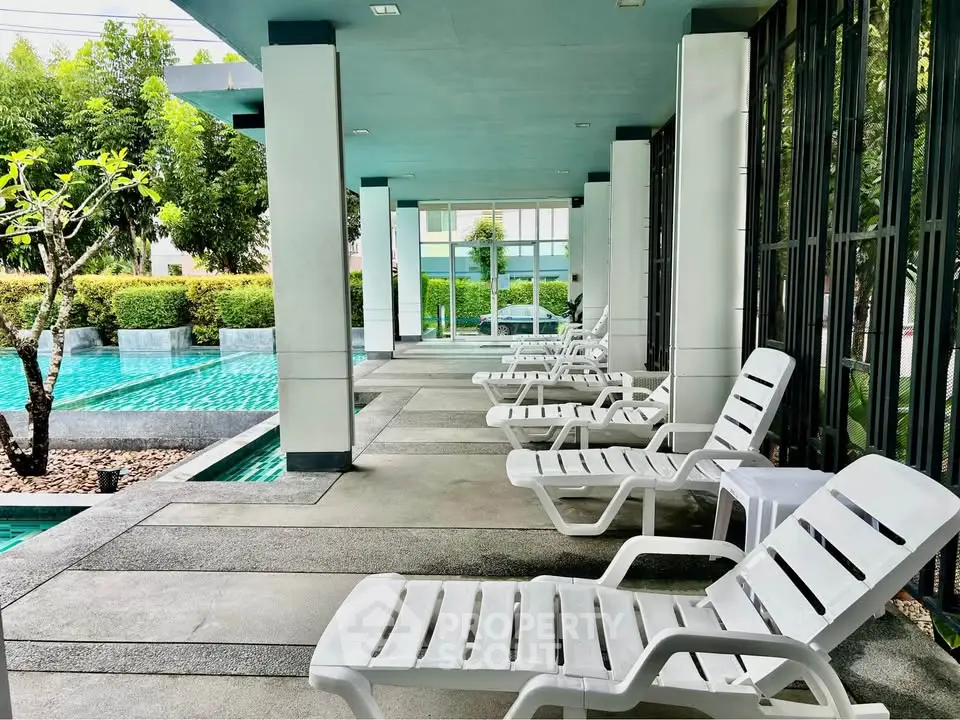 Luxurious poolside area with modern lounge chairs and lush greenery, perfect for relaxation and leisure.