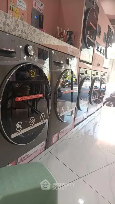 Modern laundry room with multiple washing machines in a sleek, tiled setting.