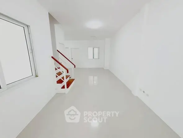 Spacious minimalist living room with staircase and large window