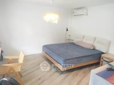 Spacious bedroom with modern decor and cozy lighting, featuring a comfortable bed and stylish wooden furniture.