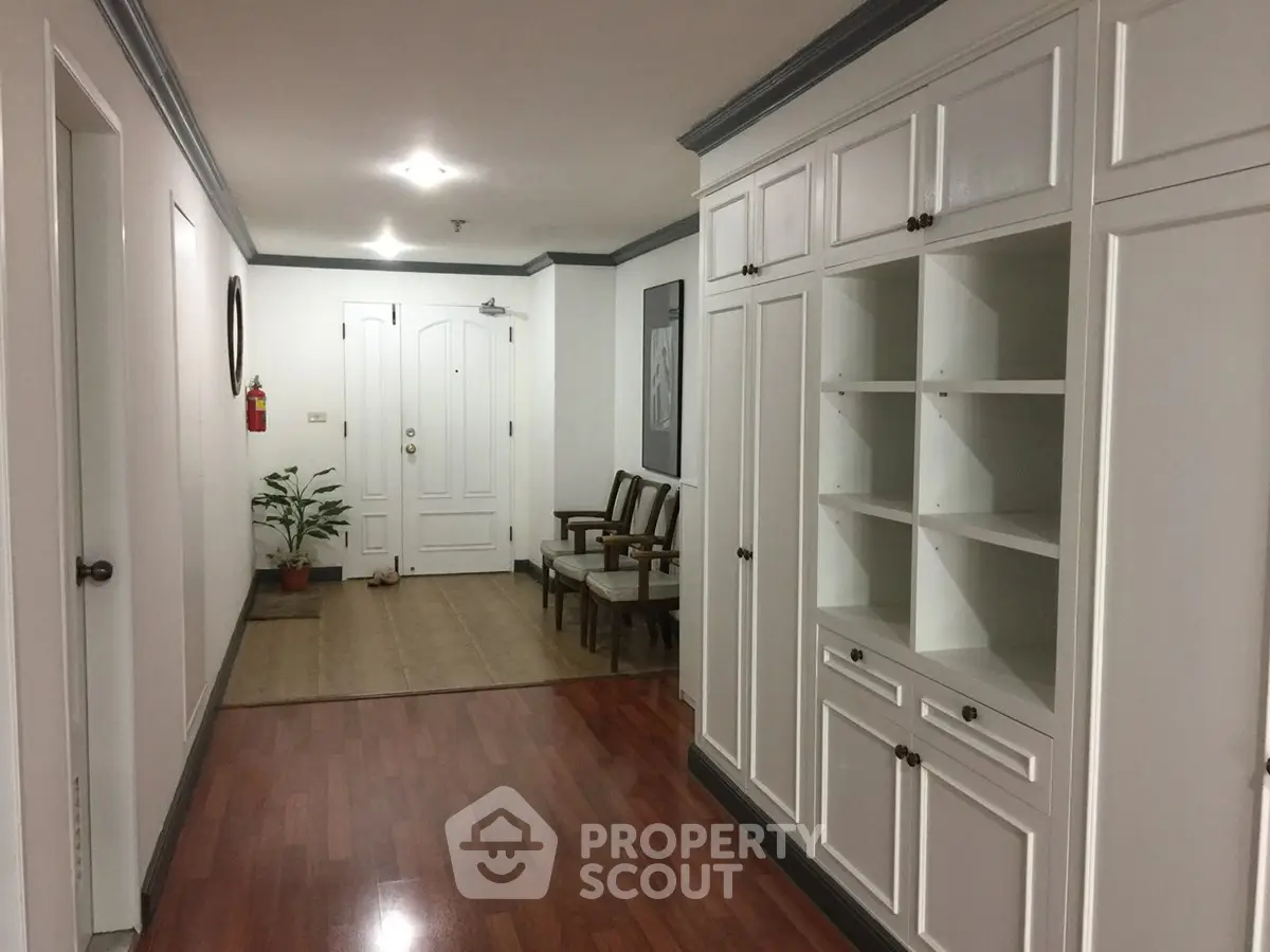 Spacious hallway with elegant wooden flooring and built-in storage cabinets