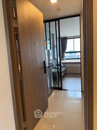 Modern apartment entrance with glass sliding doors and bright interior view.
