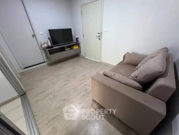 Cozy living room with modern TV setup and comfortable sofa on wooden flooring.