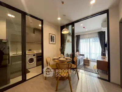Modern open-plan living room with dining area and kitchen, featuring stylish decor and natural light.