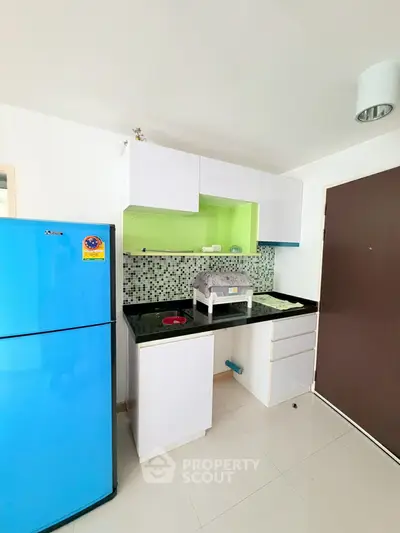 Modern kitchen with vibrant blue fridge and sleek cabinetry in a stylish apartment.