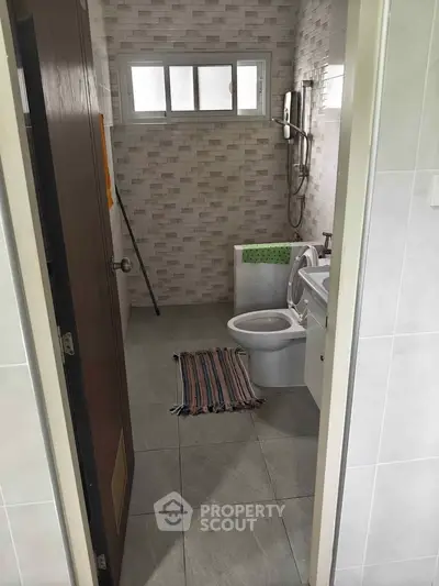 Modern bathroom with tiled walls and compact design, featuring a shower and toilet.