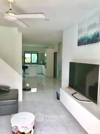 Modern living room with sleek TV setup and open kitchen layout