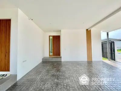 Spacious modern entrance with sleek design and tiled flooring, featuring wooden accents and ample natural light.