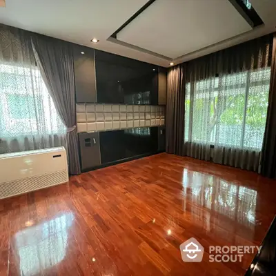 Spacious living room with hardwood floors and large windows in modern home.