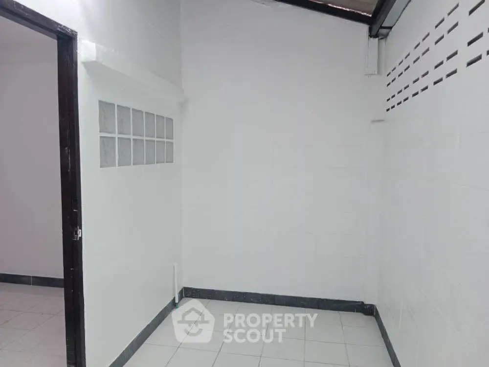Minimalist white tiled room with glass block window feature