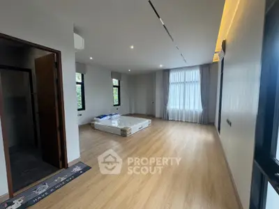 Spacious bedroom with large windows and wooden flooring in modern home