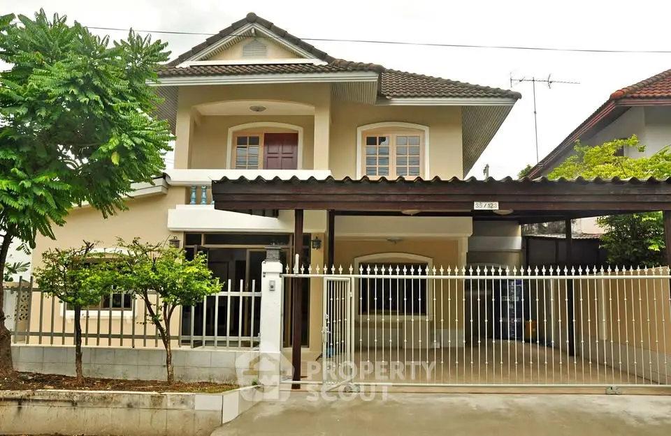 Charming two-story house with gated driveway and lush greenery in a serene neighborhood.