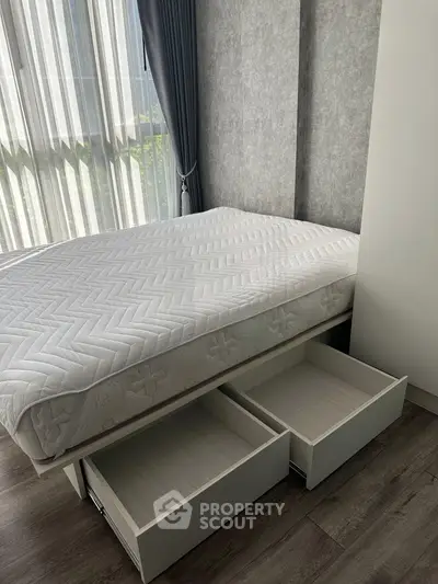 Modern bedroom with storage bed and large window, featuring sleek design and natural light.