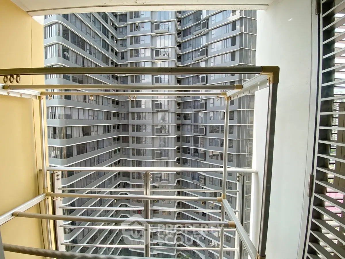 Modern high-rise building view from balcony with sleek metal railings and glass facade.