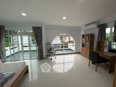Spacious modern bedroom with large windows and balcony access, featuring sleek furniture and abundant natural light.