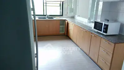 Spacious kitchen with modern wooden cabinets and microwave, ideal for culinary enthusiasts.