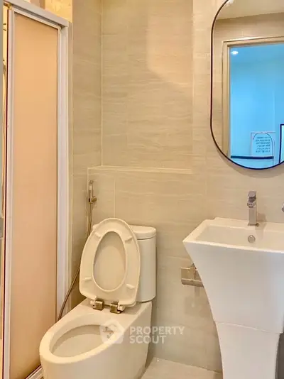 Modern bathroom with sleek fixtures and neutral tones, featuring a stylish mirror and compact design.