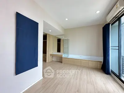 Spacious modern bedroom with wooden flooring and large windows for natural light.