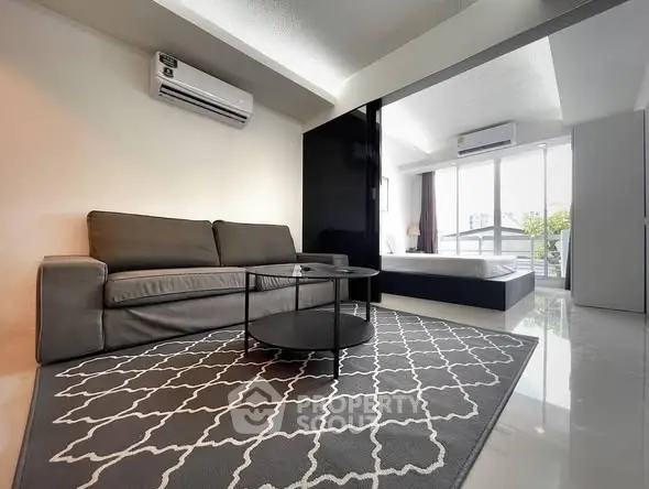 Modern living room with sleek sofa and stylish rug in open layout apartment.