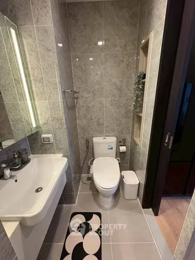 Modern bathroom with sleek design, featuring a wall-mounted sink, toilet, and stylish tile work.