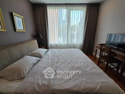 Cozy bedroom with large window and elegant furnishings in modern apartment.