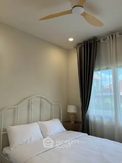 Cozy bedroom with elegant curtains and ceiling fan, perfect for relaxation.