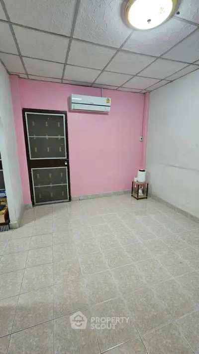Spacious room with pink accent wall and air conditioning unit, ideal for customization.