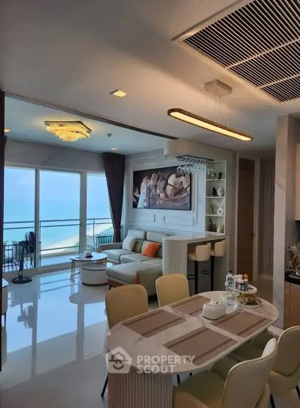 Luxurious open-plan living room with stunning ocean view and modern decor.