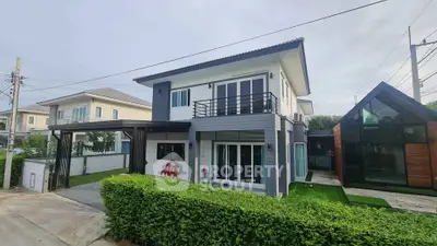 Modern two-story house with sleek design and lush green surroundings