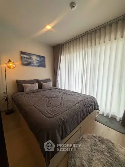 Cozy bedroom with modern decor and large window with sheer curtains