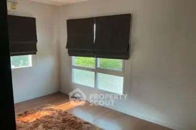 Bright and cozy room with large windows and wooden flooring, perfect for a serene living space.