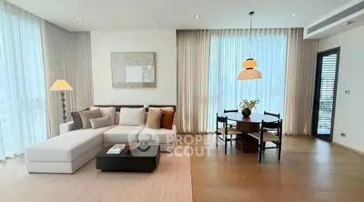 Spacious modern living room with elegant decor and dining area, featuring large windows and stylish lighting.