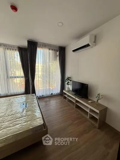 Modern bedroom with large windows, air conditioning, and stylish wooden flooring.