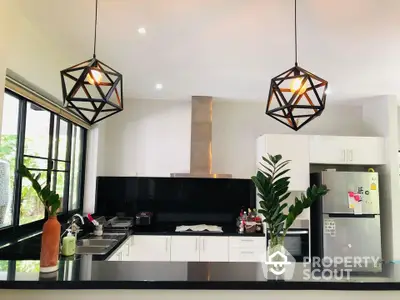 Modern kitchen with sleek black countertops and geometric pendant lights