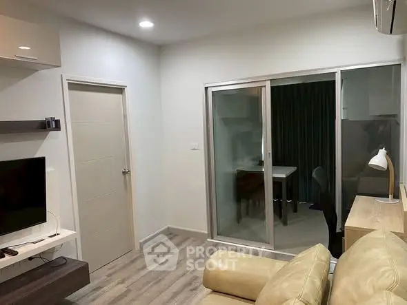 Modern living room with sliding glass door and cozy furniture in a stylish apartment.