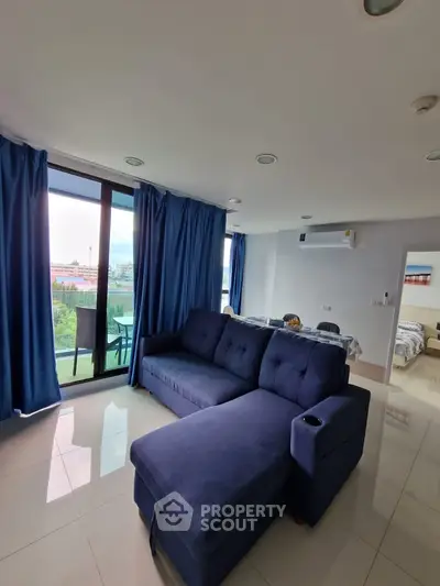 Spacious living room with modern blue sofa and large windows offering natural light and scenic views.
