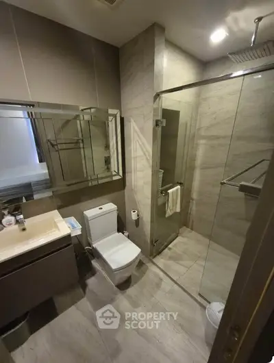 Modern bathroom with glass shower and sleek fixtures in luxury apartment.